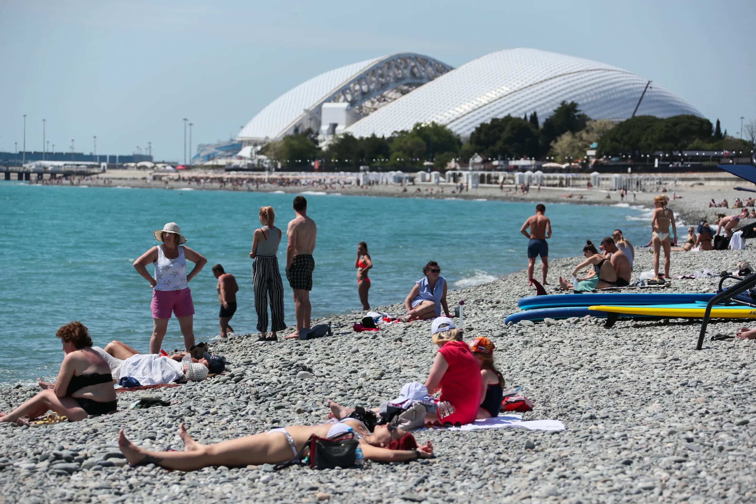Du khách nghỉ dưỡng trên bãi biển Đen tại Sochi, phía sau là sân vận động Fisht